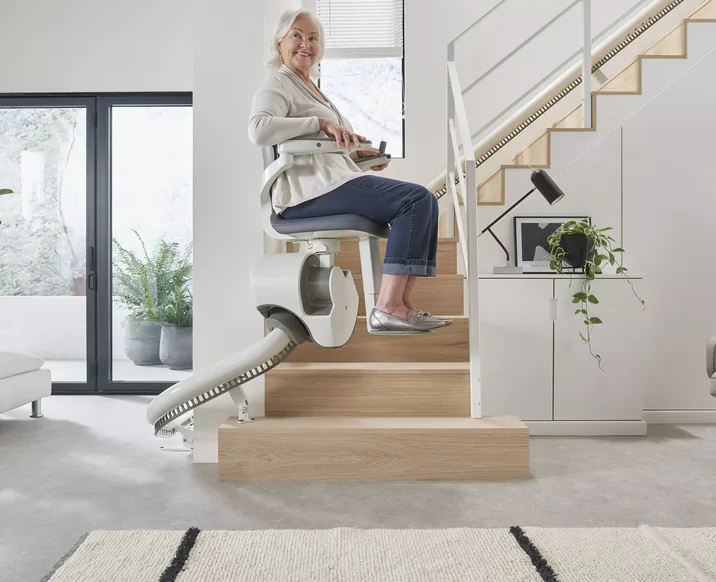Frau fährt lächelnd mit dem Flow X eine Treppe mit Kurve am Treppenanfang hinauf